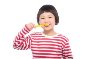 a asian girl in a red and white blouse brushing her teeth short hair cut yellow toothbrush