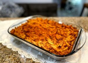 a glass dish of macaroni baked and placed on a white runner on the counter