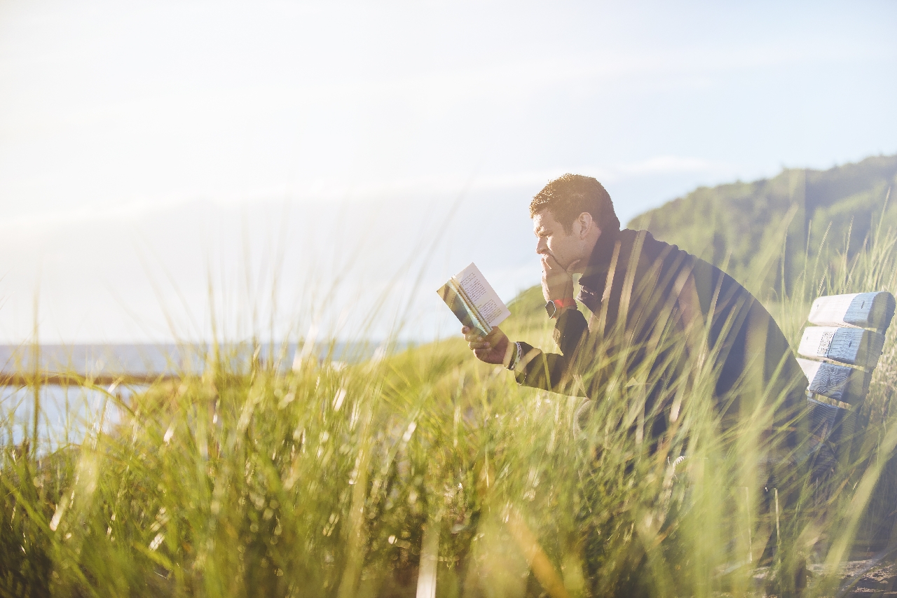 a man sitting in an open field reading and meditating