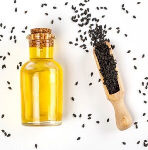 sesame oil in a glass jar with black sesame seeds on a white surface