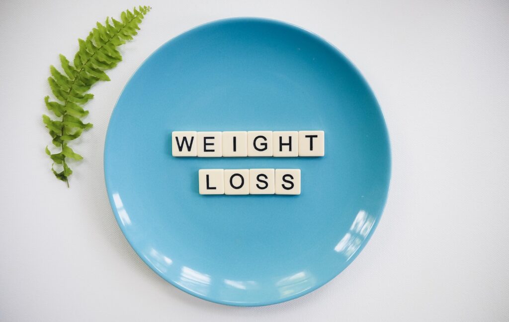 a blue plate with the words weight loss in the middle with a green fern on the left