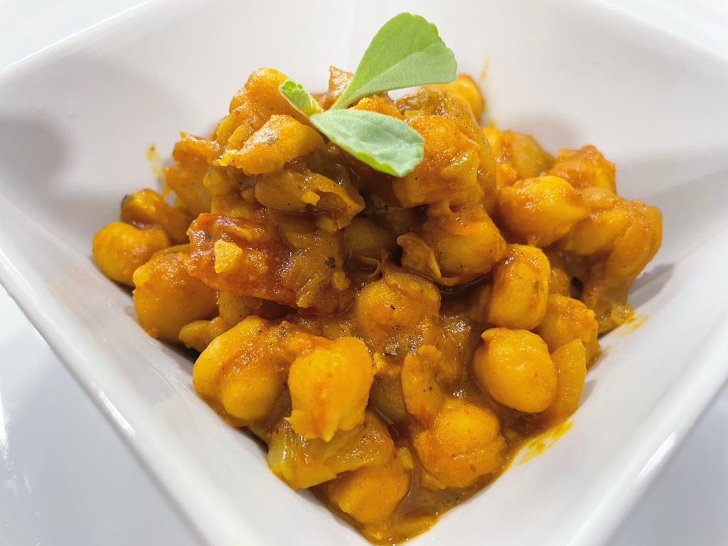 curried chickpea topped of with fresh bail leaves in a white dish