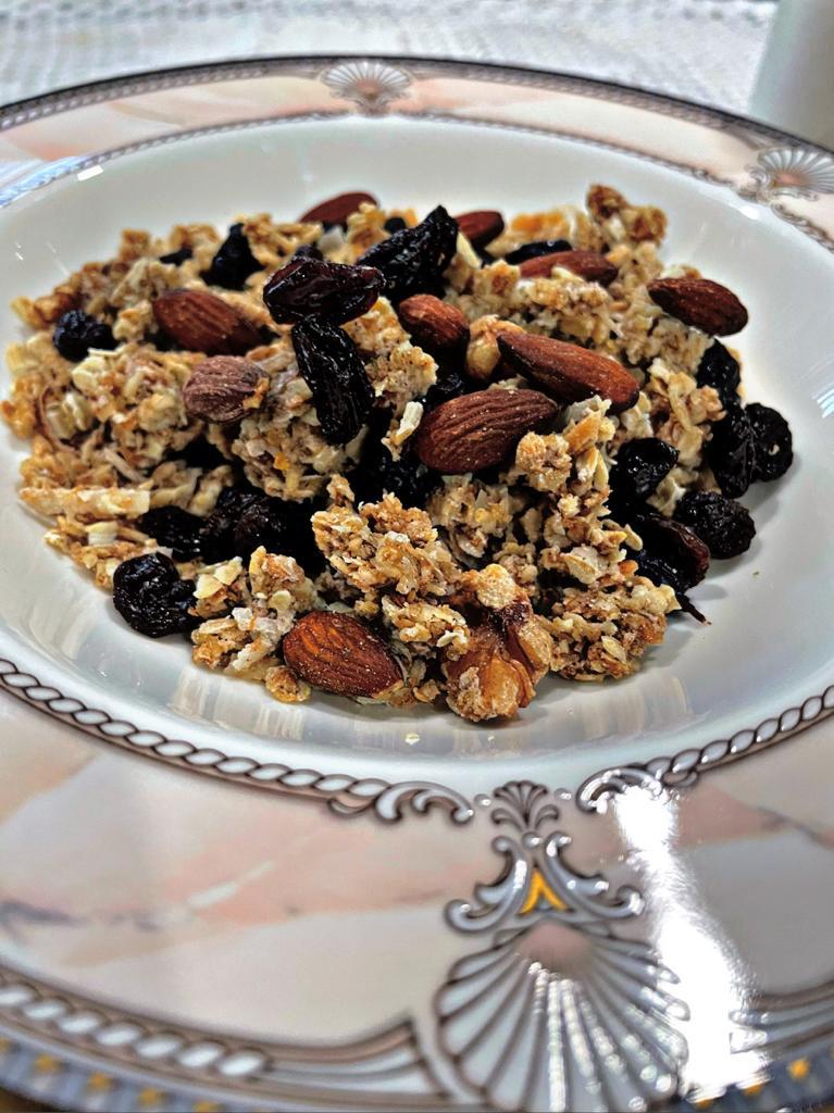 granola in a china bowl with gold trimmings with raisins almonds