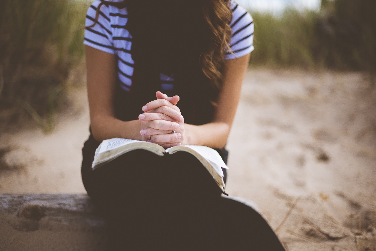 praying girl sitting outside with hands folded