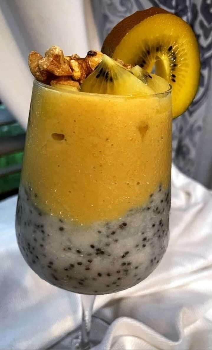 a chia soursop smoothie pudding with peach smoothie on top and kiwi and nuts on top