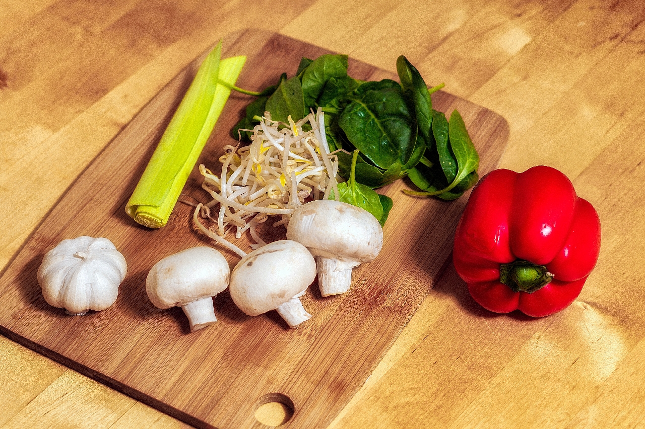 mushrooms celery sprouts spinach red bell pepper on a cutting board
