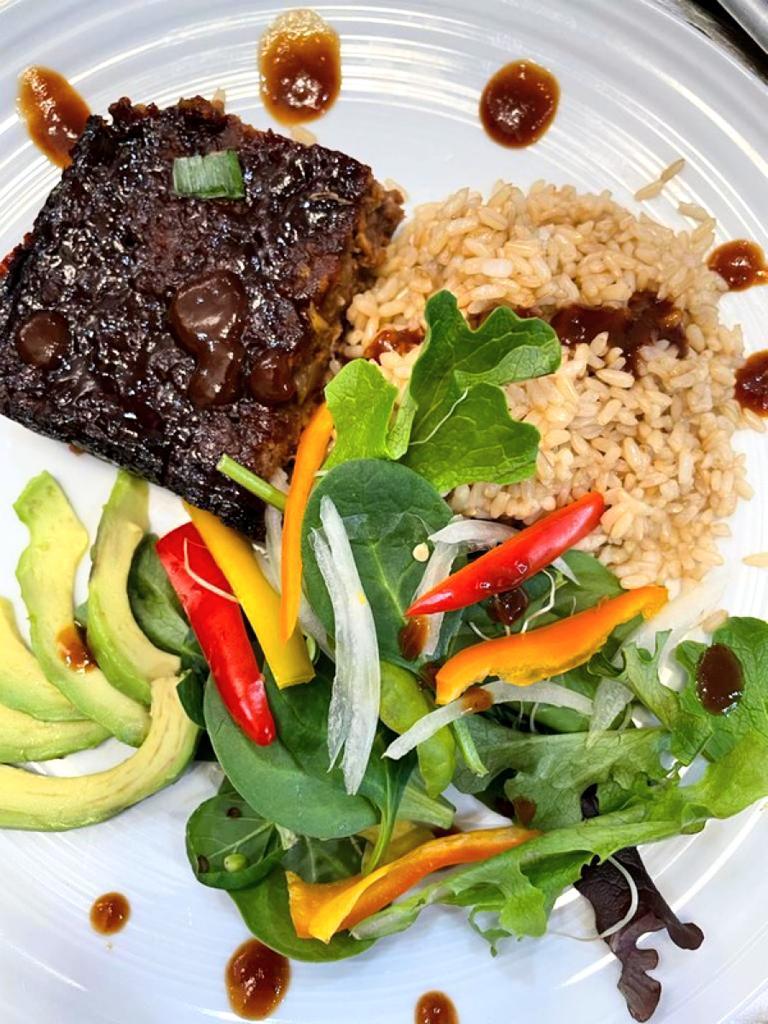 vegan meatloaf pictured with rice salad avocado and bell peppers on a white plate