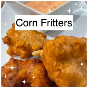 corn fritters on a white tray with a sauce