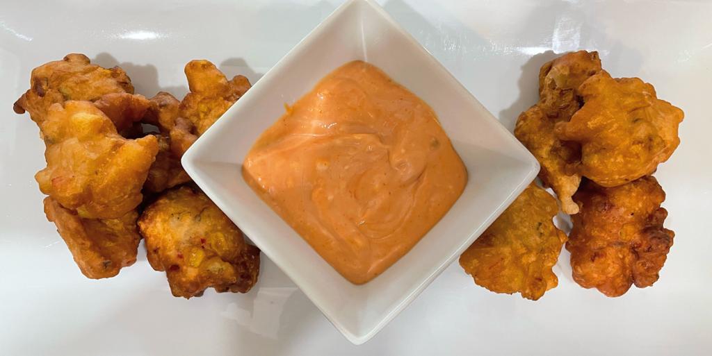 corn fritters on a tray with sauce a white tray