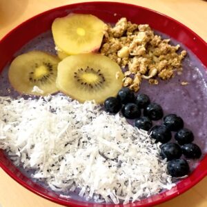 smoothie blueberry smoothie bowl topped with granola, kiwi, blueberries, coconut shreds