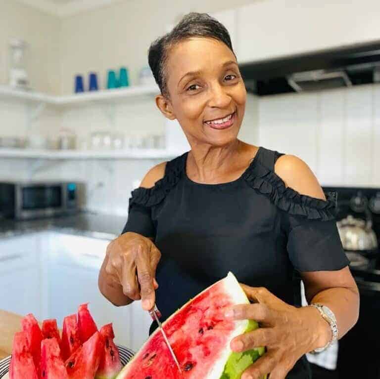 marlene mckinney with a watermelon on the counter in front of her with a knife in hand