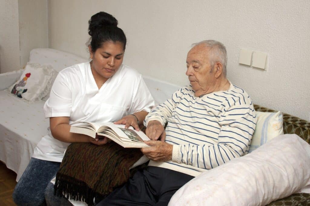 a nurse sitting talking and sharing a moment with a patient and looking through a book