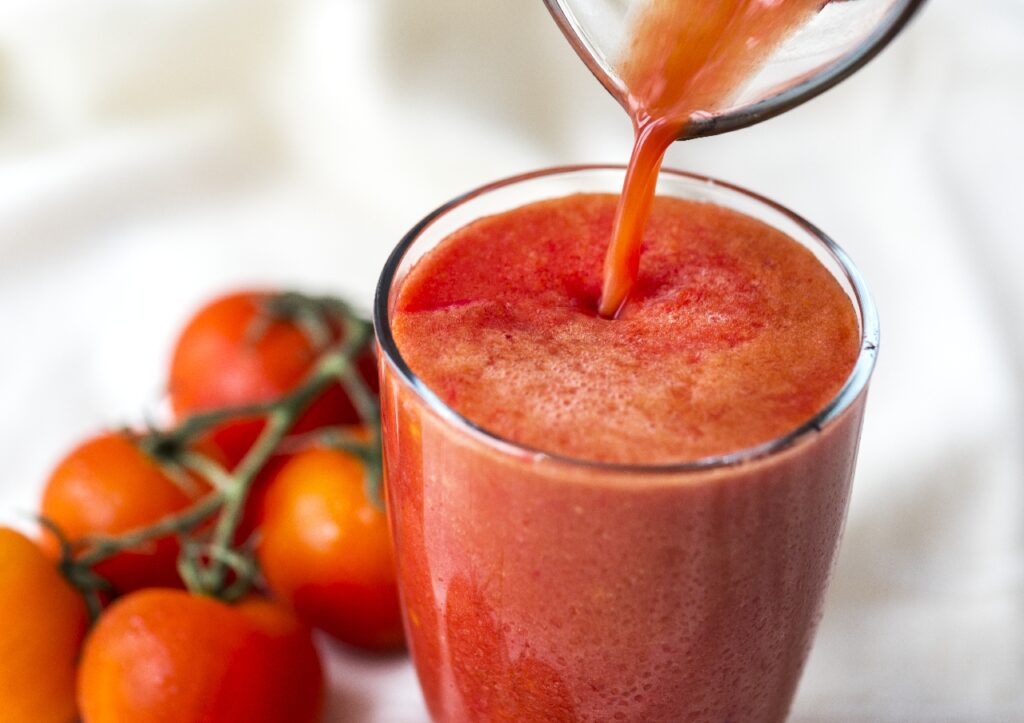 tomatoes on a counter with a glass of tomato juice.  It is the Best Juice to Drink for inflammation and it's high levels of lycopene