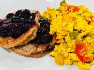 pancake with blueberry topping and on a white plate with scrambled tofu