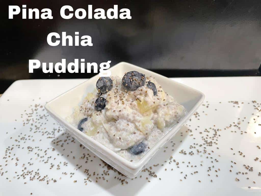 chia seeds thrown on a white plate with a triangle bowl with a white pudding with blueberries