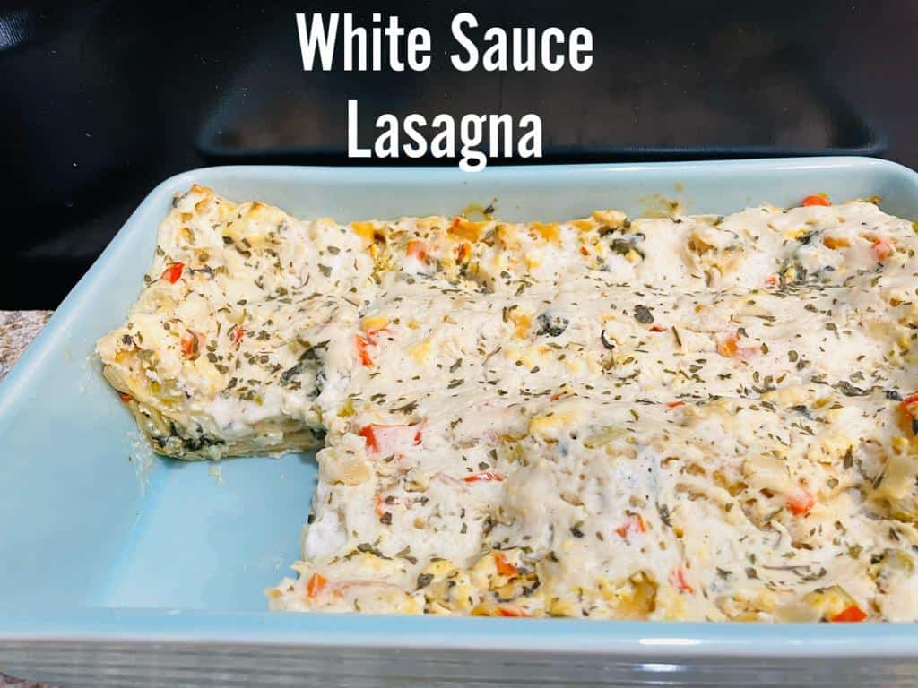 white sauce lasagna in a light green casserole dish with a black background